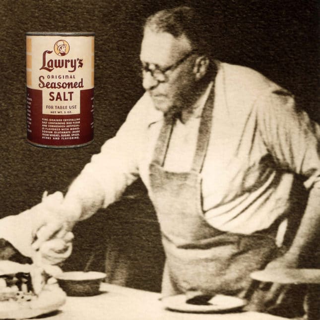 Vintage photo of Lawrence Frank in a kitchen apron poring over bowls of seasonings.