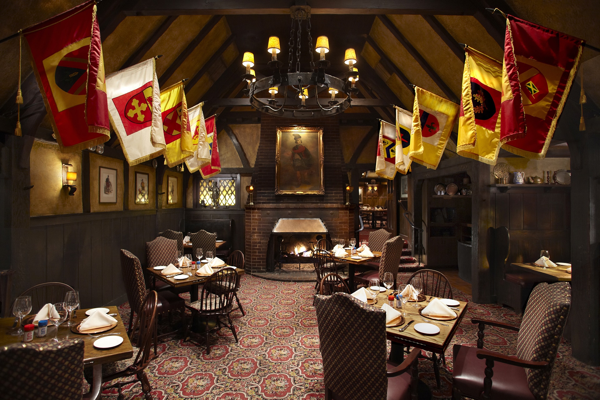 dining room at the Tam O'Shanter lined with heraldic flags and featuring a roaring fire in the fireplace