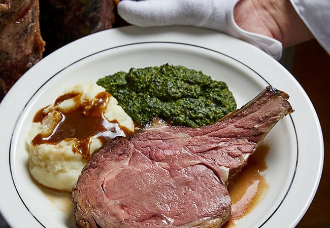 plate of prime rib with a side of creamed spinach and mashed potatoes