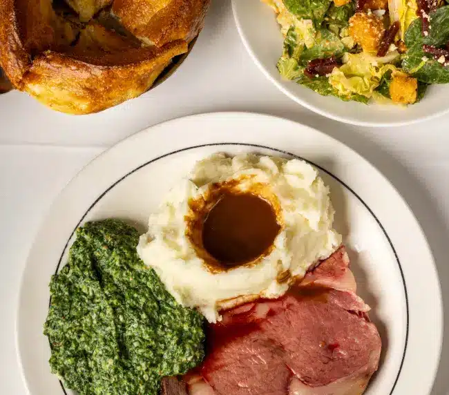 45-day dry-aged Linz Heritage Angus prime rib dinner served with Lawry's Famous Spinning Bowl Salad, mashed potatoes, and wine pairing at Lawry's Beverly Hills