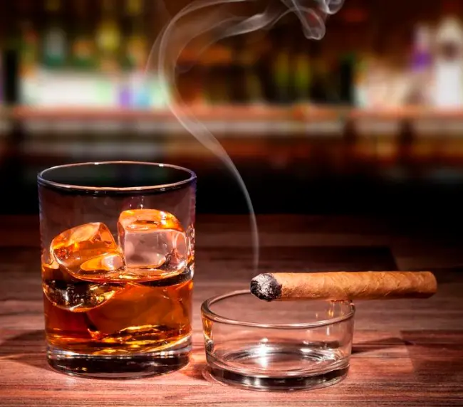 Glass of whisky on the rocks with a lit cigar on Tam O'Shanter patio